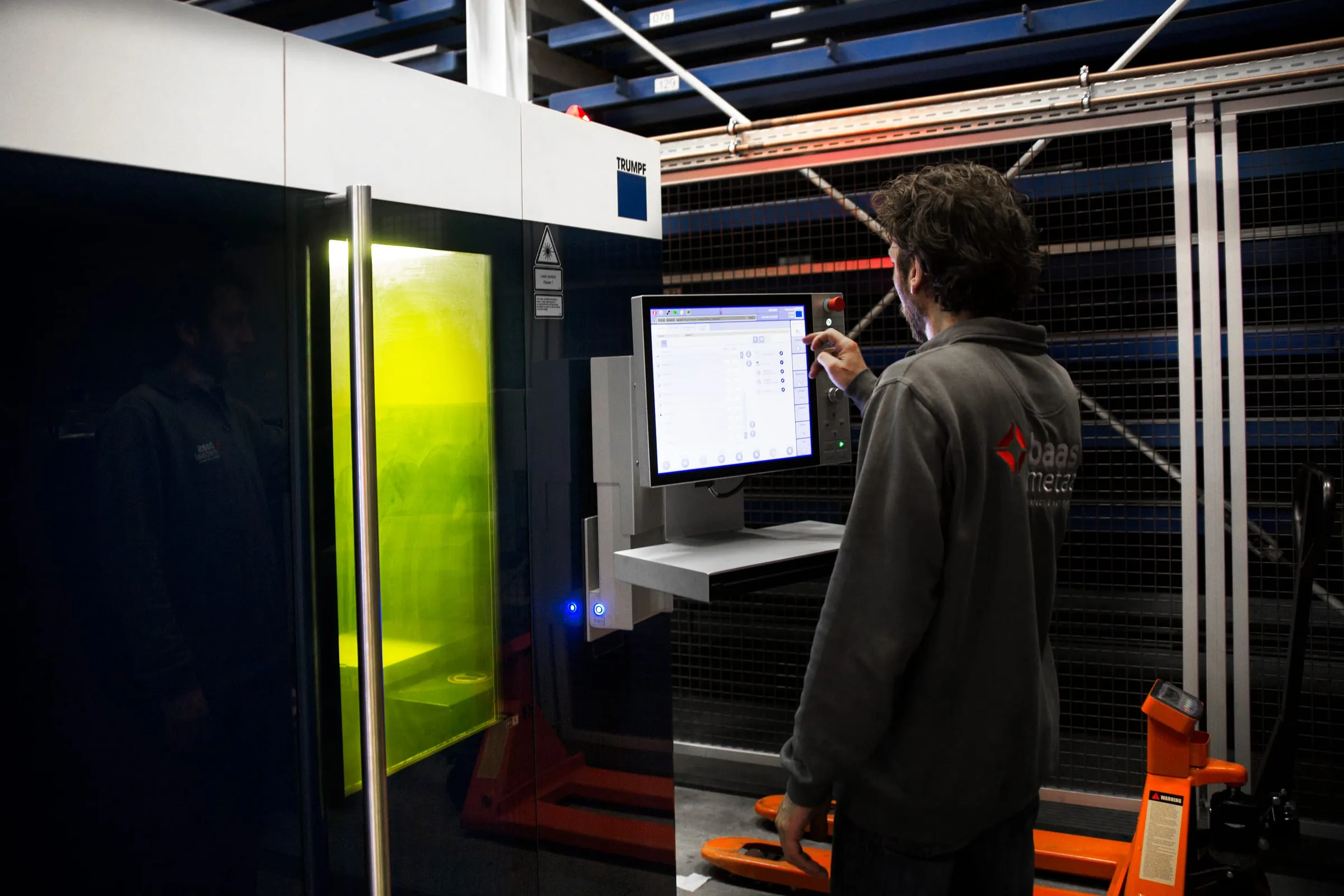 Medewerker van Baas Metaal bedient de lasersnijmachine via het bedieningsscherm in de productiehal