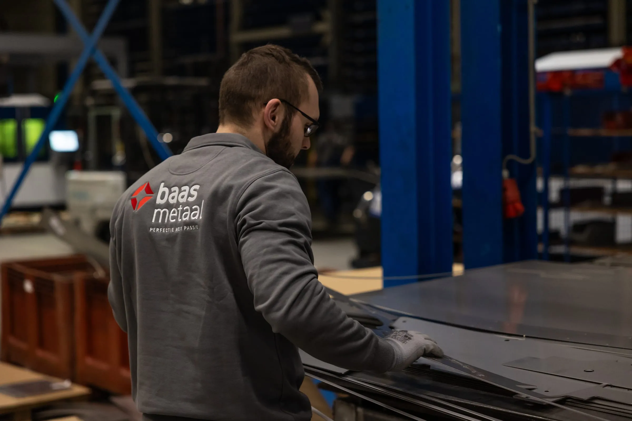Medewerker neemt gesneden plaatdelen van een stapel